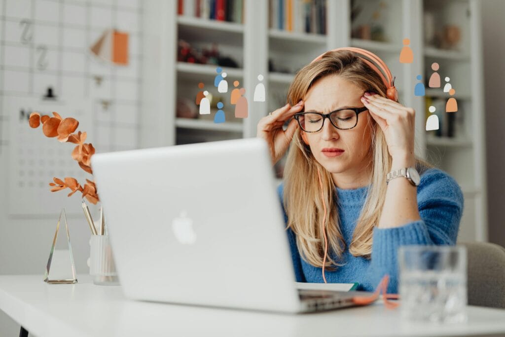 a woman looking distressed with eyes closed at a computer