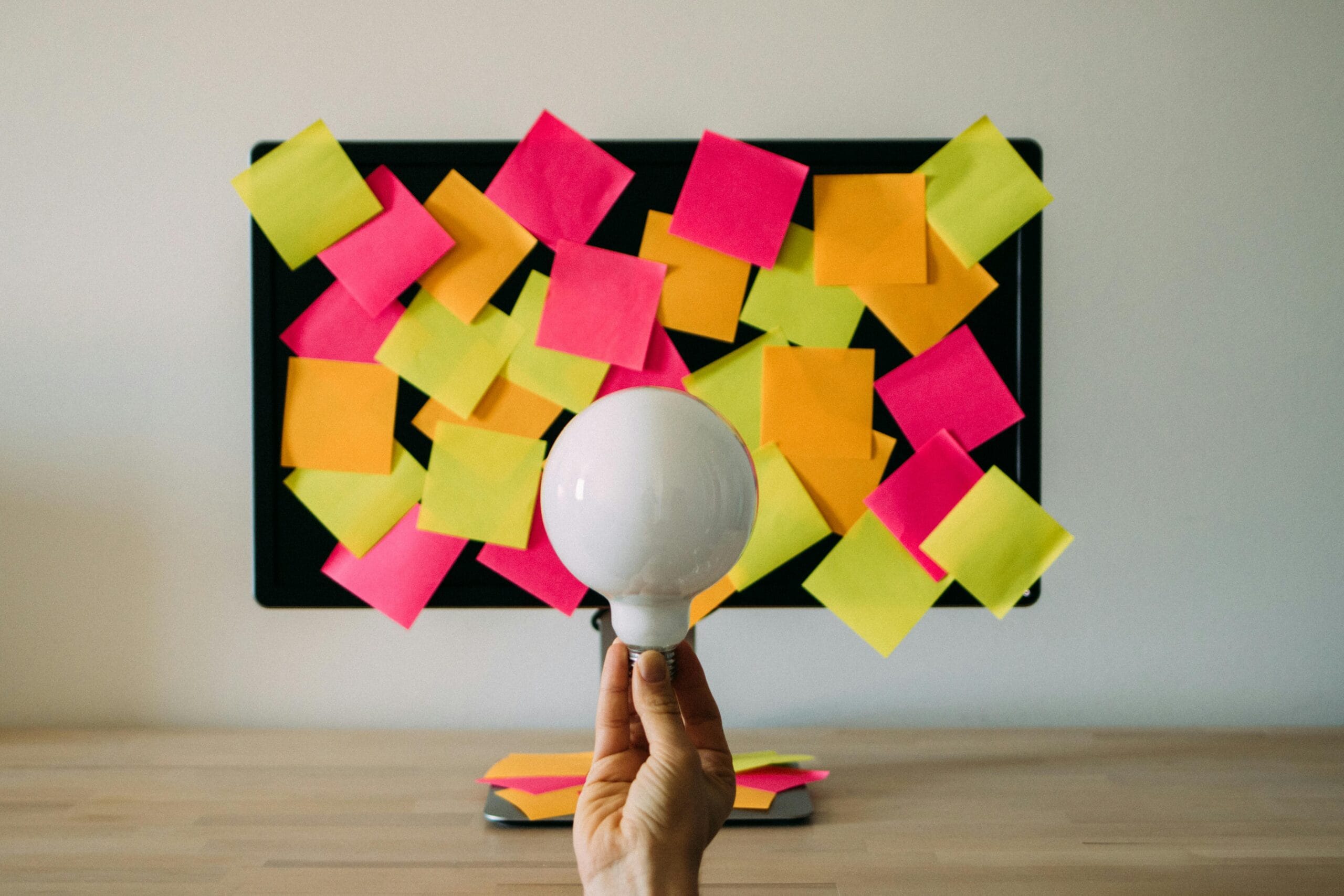 a lightbulb being held up in front of a post-it board