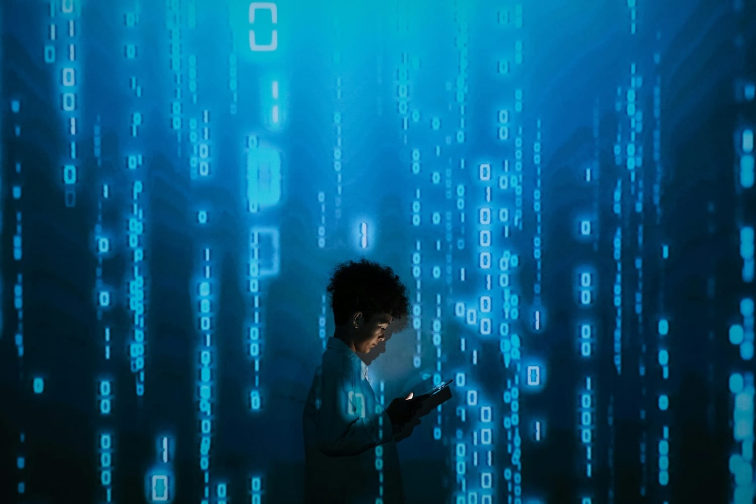 woman looking down at computer against a backdrop of computer code raining down