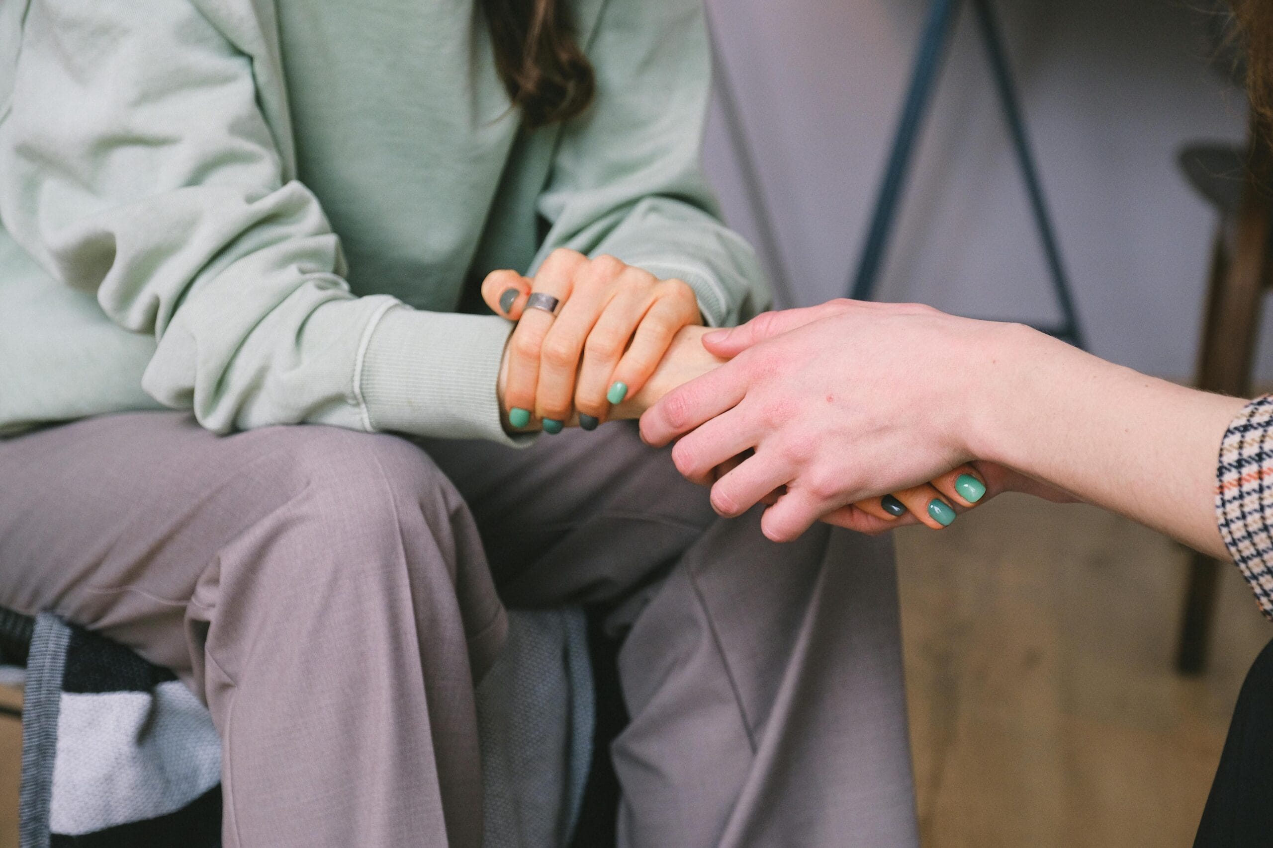 Therapist consoling a client with comforting hand holding. No faces showing.